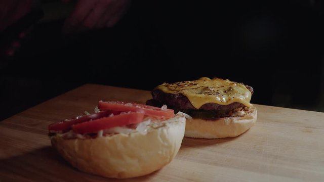 Chef preparing the burger, frying the bun on the grill, putting cutlet