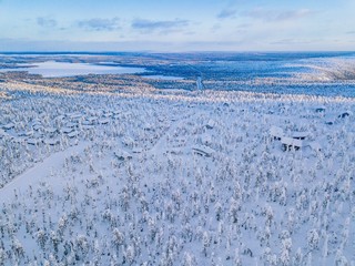 Obraz premium Aerial view of winter forest with frosty trees, rural road and village in Finland