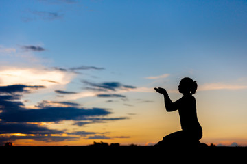 Silhouette woman praying over beautiful sky background