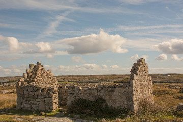 Fototapeta na wymiar Ruins of stone house in Clogh Na Mara Ireland against blue sky with clouds