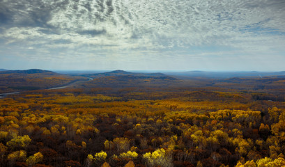Multicolored autumn forest, mountains and sky with clouds.
