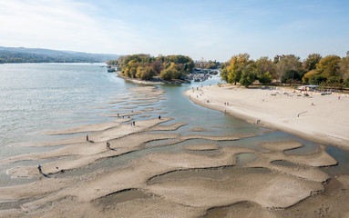 Low tide of the Danube river with people silhouettes walking on the sand islands left after water...