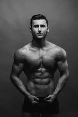 Fototapeta na wymiar Bodybuilding. Strong man posing on background. Athletic young boy showing muscles.