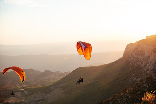 Spain, Silhouette of paraglider soaring high above the mountains at sunset