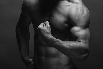 Naklejka premium Bodybuilding. Strong man posing on background. Athletic young boy showing muscles.