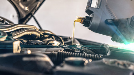 Fototapeta Oil Service - Mechanic fills up the enigne with engine oil obraz