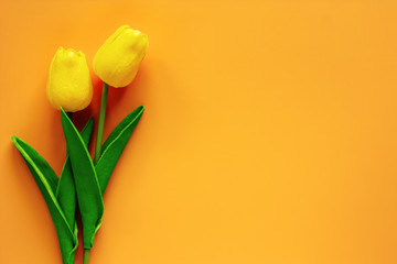 Artificial tulips on yellow background for nature decoration and springtime concept