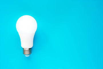 Glowing LED light bulb on blue background for energy savings concept