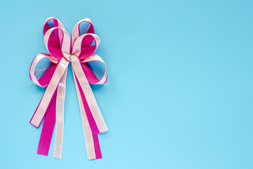 Pink fabric ribbon and gift bow on blue background