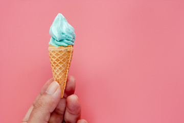 Hand holding ice cream cone on pink background for sweet and refreshing dessert concept