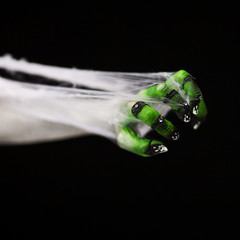 Creepy halloween hand in green and white with spider web, zombie hand on black background