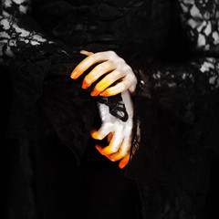 Creepy halloween vampire hands close up in red orange and silver on black, can be used as background