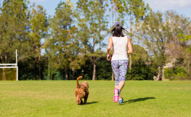 young woman jogging with her pet golden doodle dog