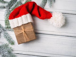 Gift box with Christmas tree branches in Santa's red hat
