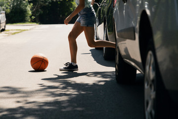 Girl running with ball on pedestrian crossing next to cars
