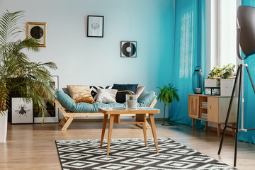 Gallery of posters on empty white wall in stylish living room interior with urban jungle and...