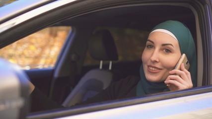 portrait of a beautiful woman driver in hijab with a phone in the car
