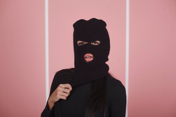 Pathetic girl in balaclava, on a pink background