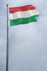 Fototapeta na wymiar Worn and tattered Hungary flag blowing in the wind on a cloudy day