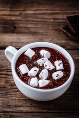 A cup of hot chocolate or cocoa with marshmallows on wooden background