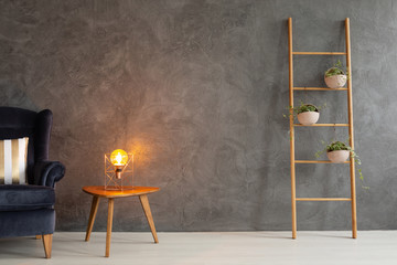 Modern lamp on elegant wooden table in simple and trendy interior with dark empty wall, real photo...