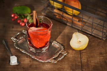 Glass of Cider pear cocktail or lemonade, cinnamon sticks, anise stars on wooden background.