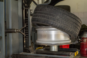 Summer car tire half taken from the disk to perform tire mounting and fitting on a special machine in the workshop for repairing vehicles before the start of the winter season