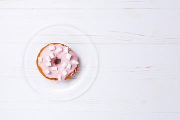 Pink donut in sugar glaze on a transparent plate