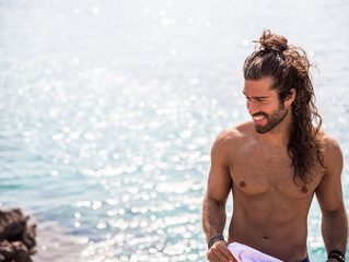 young man with long hair posing next to the coast