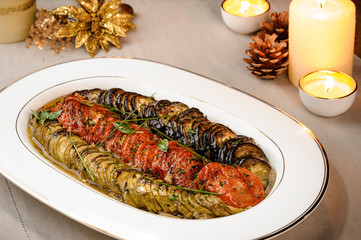 Delicious Ratatouille. Roasted zucchini with tomato and eggplant on a ceramic dish. Decorated table...