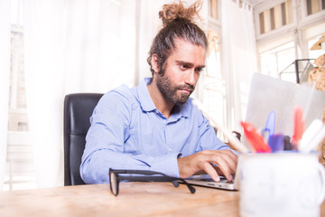 young man with long hair working with his laptop at home