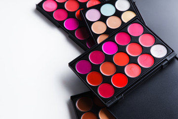 Various lipstick and eye concealer palettes with lots of colors isolated on white background....