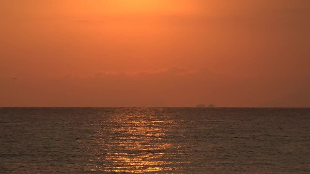 Cielo rosso al tramonto su mare e nave all'orizzonte