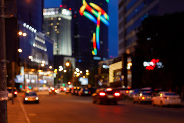 A blurred background of city centre with heavy car traffic and skyscrapers around.