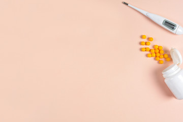 Medical electronic thermometer, drops and pills on pink background. Health care concept. Top view. Copy space. Flat lay
