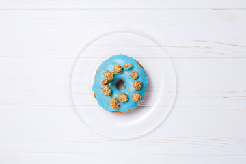 Blue donut in sugar glaze on a transparent plate