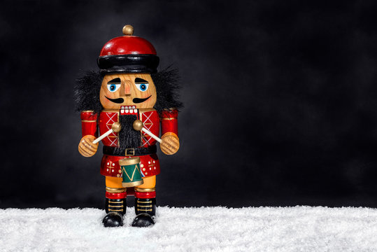 Merry Christmas: Traditional colorful vintage wooden red nutcracker little drummer boy doll isolated on black dark background and room copyspace for text - concept festive Christmas decoration decor