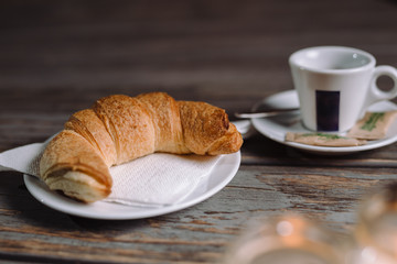 Croissant and coffee on wooden table