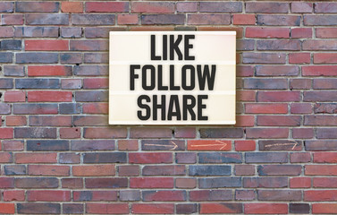 Like, Follow and Share in light box on brick wall