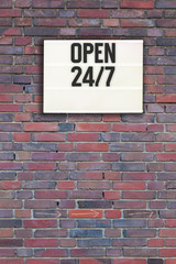 Fototapeta na wymiar Open 24 by 7 in light box on brick wall