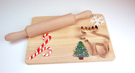Wooden rolling pin and cutting board, cookie cutters for a gingerbread man, candy canes, snowflake, Christmas tree. Christmas and New Year holiday background concept. Copy space for text.