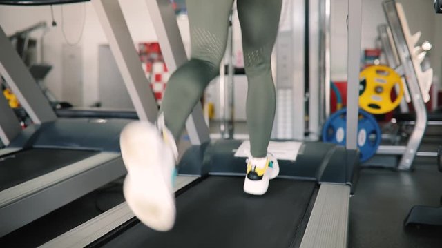 Female legs running on a treadmill in gym