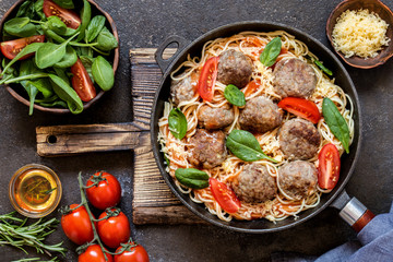 meat balls with pasta spaghetti with spinach, fresh tomatoes in a frying pan on a cutting Board