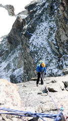 female mountain climber rappelling off a high alpine peak in the Swiss Alps above Zermatt