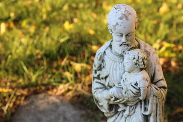 Religious statue on gravestone in cemetery 