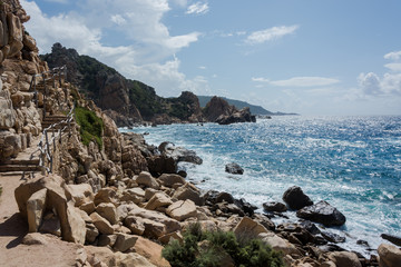 Fototapeta na wymiar Costa rocciosa sul mare in pieno giorno con sentiero