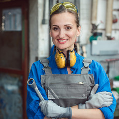 Woman worker in her metal workshop posing with tools for the camera