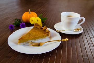 Slice of fresh home made pumpkin pie on wooden surface.  Traditionally served in fall or for thanksgiving in the United States.  Selective focus