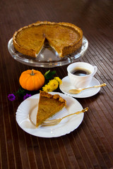 Slice of fresh home made pumpkin pie on wooden surface.  Traditionally served in fall or for thanksgiving in the United States.  Selective focus