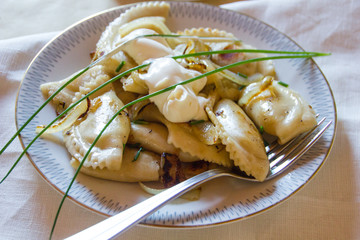Polish traditional salty dumplings  called Pierogi with white cream served on a white plate....